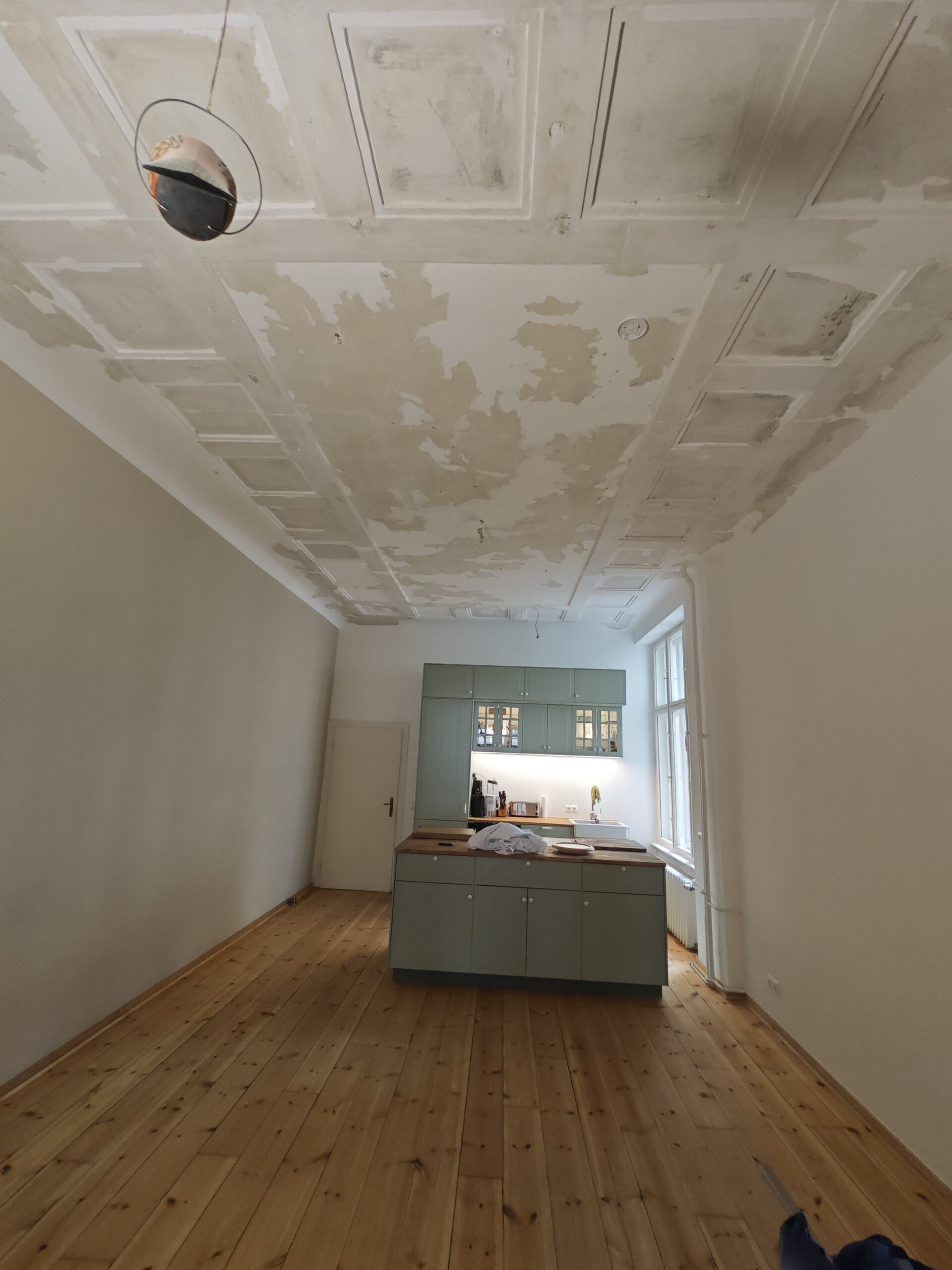 Küche mit Holzfußboden und renovierungsbedürftiger Decke in einem Altbau